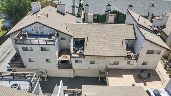Aerial front view of a multi-story residential building with balconies and a flat rooftop.