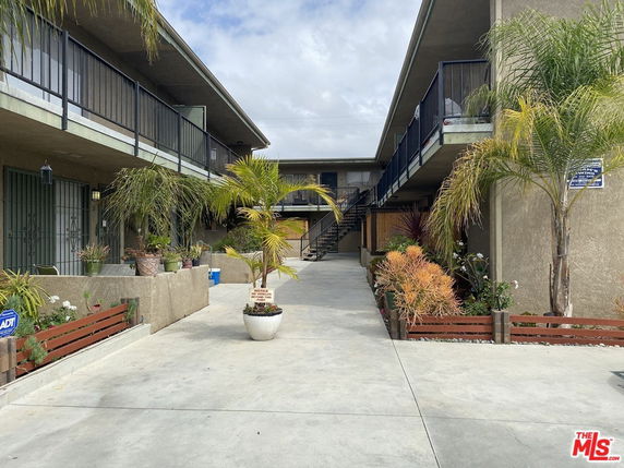 Front view of an apartment building with balconies and a central pathway.