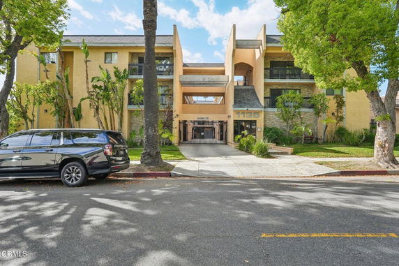 Front view of a multi-story residential building with balconies and a gated entrance.