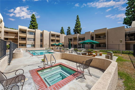 Outdoor swimming pool area with buildings in the background.