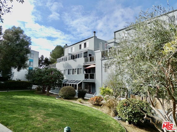 Front view of a multi-story building with balconies and large windows.