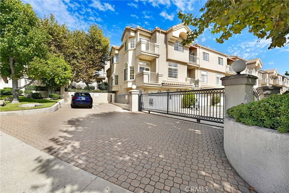 Front view of a multi-story building with a gated entrance and driveway.