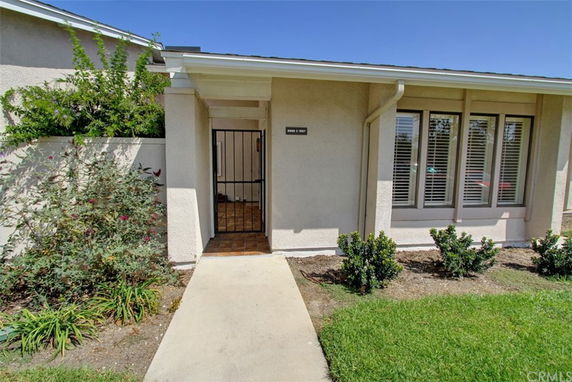 Front view of a single-story house with a gated entrance and large windows.