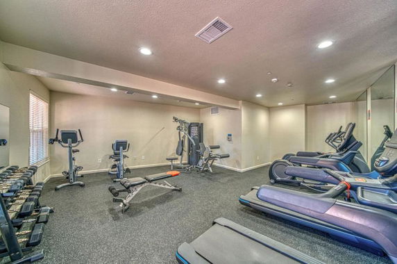 Interior view of a gym area with exercise equipment including treadmills and weights.
