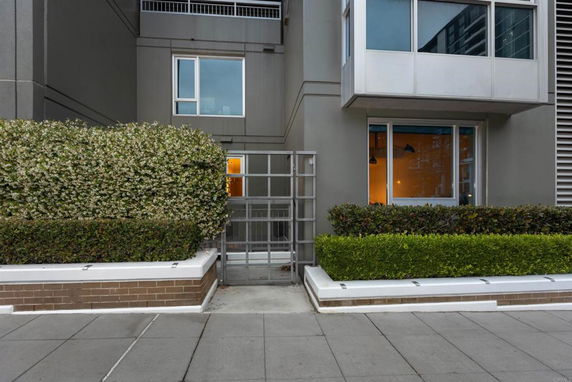 Front view of a modern building with large windows and hedge landscaping.