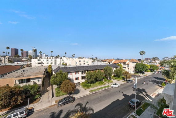 Panoramic view of a residential neighborhood with multiple buildings and a cityscape in the background.