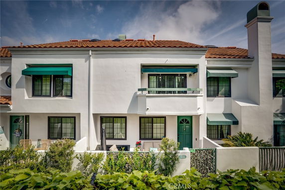 Front view of a multi-story building with green awnings and a tiled roof.