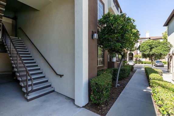 Front view of a residential building with an exterior staircase and landscaped walkway.