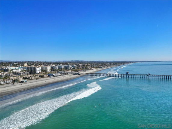 Aerial view of a coastal city with a long pier extending into the ocean.