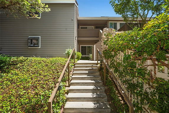 Front view of a multi-story residential building with stairs leading to the entrance.