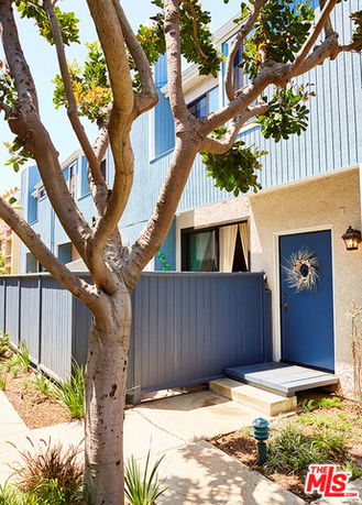 Front view of a two-story blue townhouse with a gated entrance.