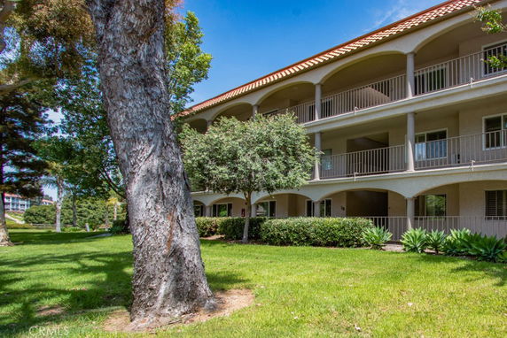 Front view of a three-story building with balconies and a tiled roof.