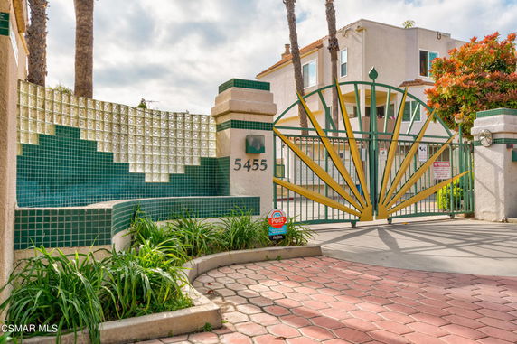 Front view of a building with a decorative green and yellow metal gate and tiled walls.