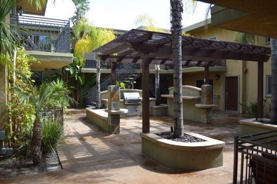 Outdoor courtyard area with a pergola and surrounding vegetation.