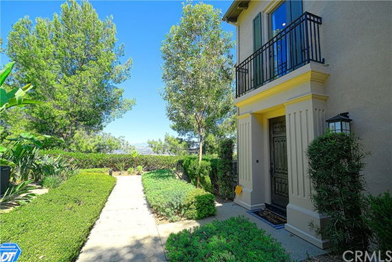 Front view of a two-story house with a balcony above the entrance and landscaped pathway.