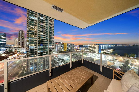 High-rise balcony view overlooking cityscape and water at sunset.