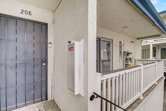 Front view of a residential unit with metal security door and a small balcony.