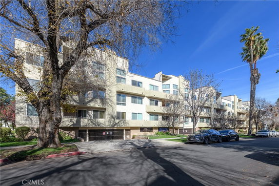 Front view of a multi-story apartment building with balconies and large windows.