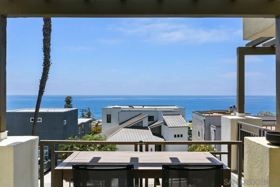 View from a balcony overlooking modern houses and the ocean in the background.
