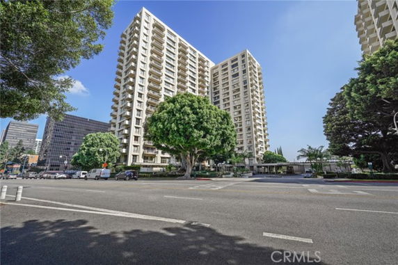 Front view of tall apartment buildings with trees and a street in the foreground.