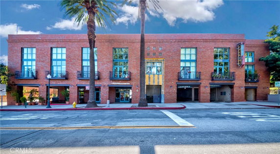 Front view of a multi-story brick building with large windows and balconies.
