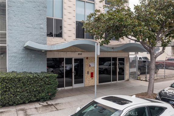 Front view of a building entrance with glass doors and a wavy overhang.
