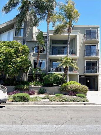 Front view of a multi-story building with balconies and a gated entrance.