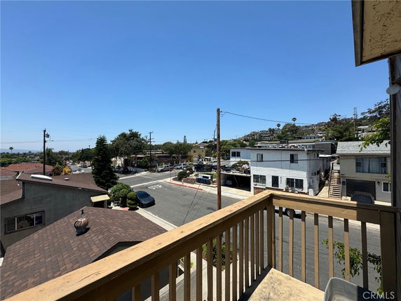 View from a balcony overlooking a residential area with streets and houses.