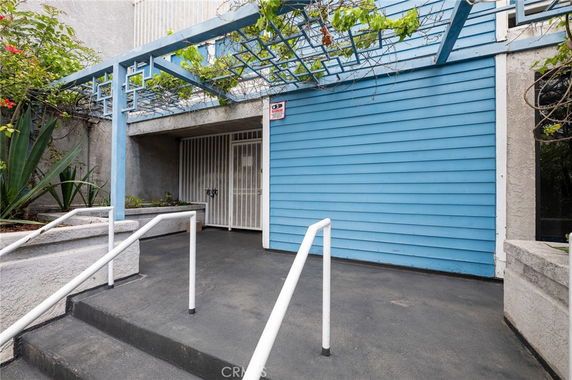 Entrance view of a building with blue siding and white security gate.