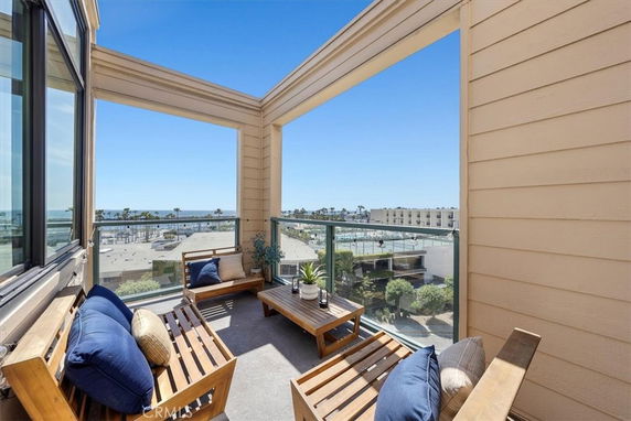 Outdoor balcony seating area with a panoramic view of the ocean and surrounding buildings.