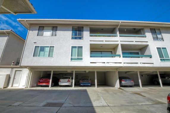 Covered parking area beneath a multi-story residential building.