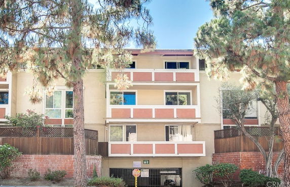 Front view of a multi-story residential building with balconies and an entrance.
