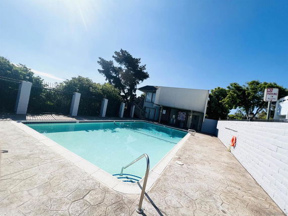 Outdoor swimming pool with surrounding fence and adjacent building.