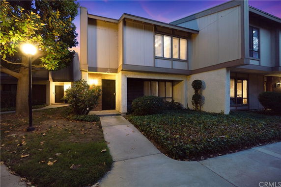 Front view of a multi-story townhouse with a lit pathway at dusk.