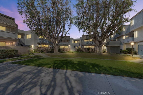 Front view of a multi-story residential building with balconies and surrounding pathways.