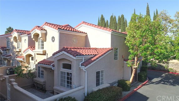 Front view of a two-story house with a red-tiled roof and stucco exterior.