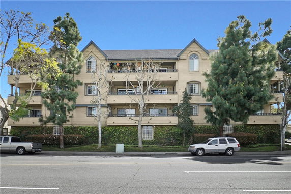 Front view of a multi-story apartment building with balconies and triangular rooflines.