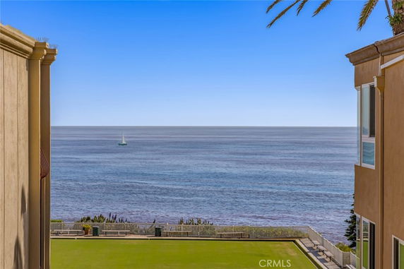 Ocean view between two buildings with a sailboat visible in the distance.