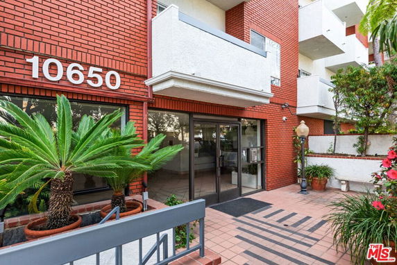 Front view of a brick residential building entrance with glass doors.