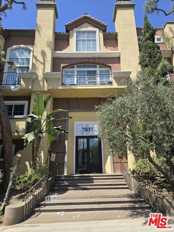 Front view of a multi-story building with large windows and entrance steps.