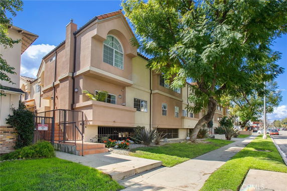 Front view of a multi-story residential building with arched windows and a gated entrance.