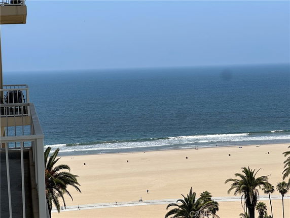 Panoramic view of a beach and ocean with visible palm trees from a building balcony.