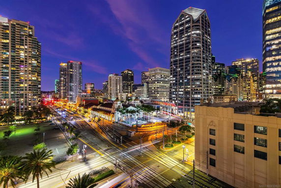 Panoramic view of a city skyline at night with illuminated skyscrapers and busy streets.