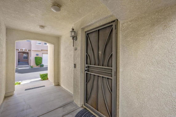Front view of a building entrance with a decorative metal door and outdoor lighting.