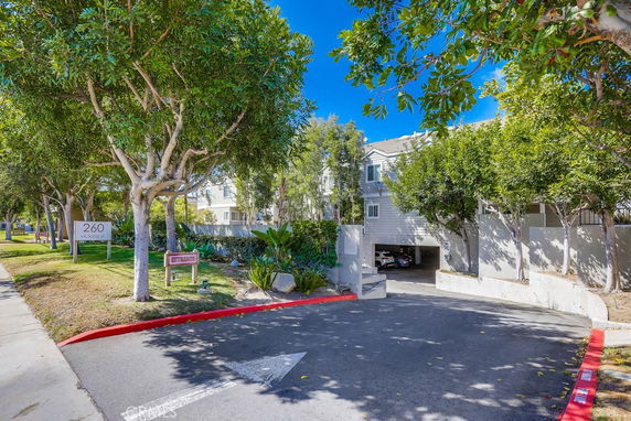 Entrance to a parking area under a residential building with trees around.