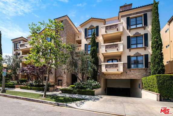Front view of a multi-story residential building with balconies and a stone facade.