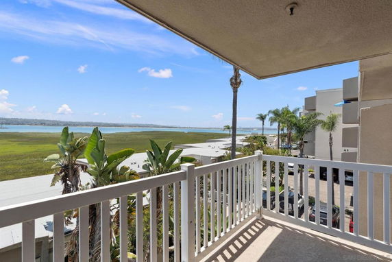 View from a balcony overlooking a large body of water with surrounding greenery and palm trees.
