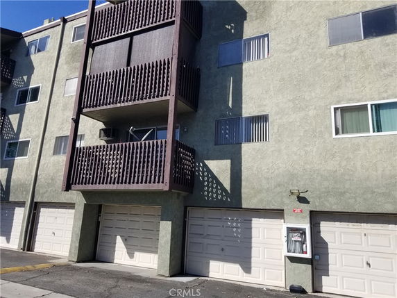 Front view of a multi-story building with garages and balconies.