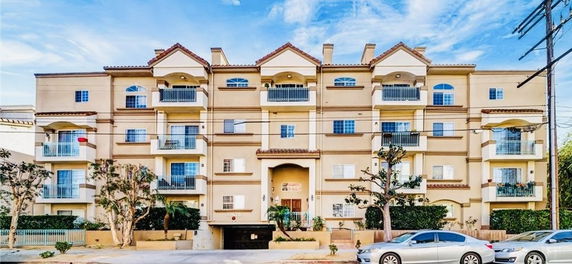 Front view of a multi-story apartment building with balconies and a central entrance.