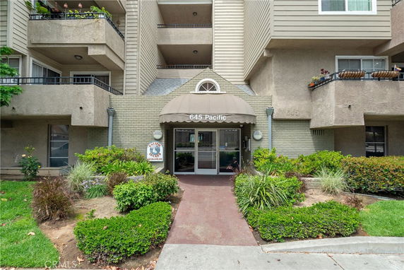 Front view of a multi-story residential building with balconies and an entrance canopy.